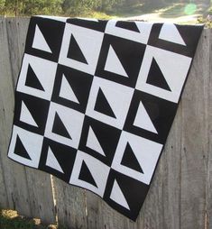 a black and white quilt hanging on a fence