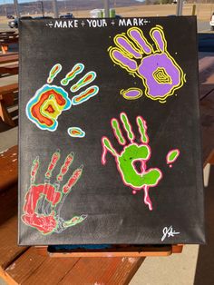 a hand and foot prints are displayed on a black canvas with wooden benches in the background