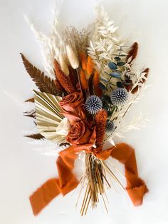 an arrangement of dried flowers with orange ribbons