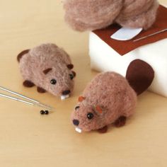 two stuffed animals sitting on top of a table next to sewing needles and needle tips