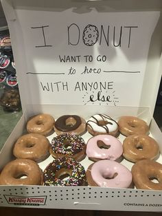 a box filled with lots of donuts sitting on top of a counter next to a sign that says i donut want to go