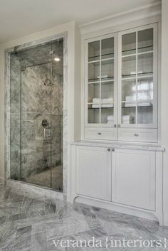 a walk in shower sitting next to a white cabinet and counter top with glass doors