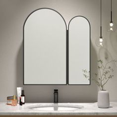 a bathroom vanity with two mirrors and a vase on the counter top next to it