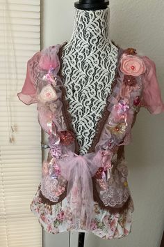 a mannequin is adorned with pink and brown fabric, flowers, and sequins