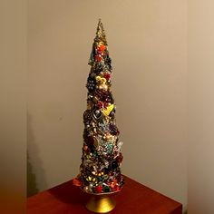 a christmas tree made out of many different types of ornaments on a wooden table next to a white wall