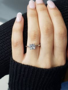 a woman's hand with a diamond ring on her left hand and a black sweater