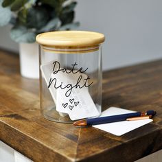 a glass jar with some writing on it and a pen sitting next to the jar