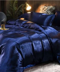 a bed with blue sheets and pillows on top of it, next to a lamp