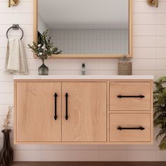 a bathroom vanity with mirror, towel rack and plants