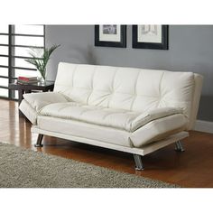 a white futon sofa sitting on top of a hard wood floor next to a window