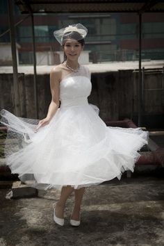 a woman in a white dress and veil posing for the camera with her hands on her hips