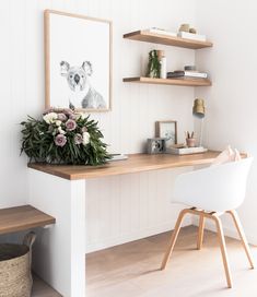 a white desk with flowers on it and some shelves in the back ground, next to a chair