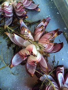 some purple flowers are laying on a blue surface and sprinkled with green leaves