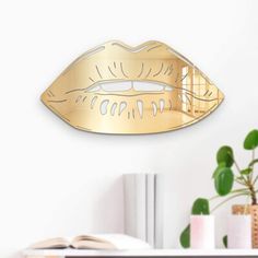 a wall mounted mirror that has a gold lips design on the front and back of it