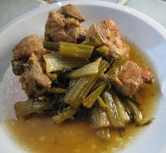 a white plate topped with meat and vegetables covered in gravy on top of a table