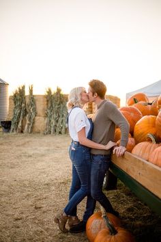 a man and woman kissing in front of pumpkins