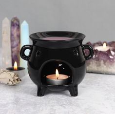 a black caulder with a lit candle in it on a table next to candles