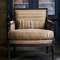 an old chair sitting in front of a bookcase with books on it's shelves