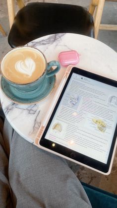 a tablet sitting on top of a table next to a cup of coffee and saucer