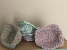 three crocheted baskets sitting on top of a wooden table