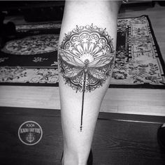 a black and white photo of a person's leg with a dragonfly tattoo on it