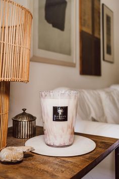 a white candle sitting on top of a wooden table next to a wicker basket