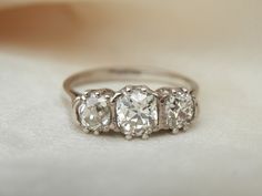 Here we have a beautiful handmade antique three stone diamond ring featuring 1.25ct of old mine cut diamonds I have been searching for a while for a trilogy of this size and was delighted to acquire this piece for the store. Graded 'antique' this ring would settle comfortably into the early Art Deco 1920's period, which was an iconic period of jewellery production.  The shank is palladium which is harder and more durable than gold and was first used in jewellery around this time... and the stones as I would expect, are set in platinum. Characterized by their cushion-like shape, high crown and large facets, old mine cut diamonds were originally crafted in the late 17th to the late 19th Century. The name derived from a time when diamond production from Africa began to eclipse production from Diamond Three Stone Ring, Stone Diamond Ring, Three Stone Diamond Ring, Trilogy Ring, Art Deco 1920s, Three Stone Diamond, Three Stone Ring, Antique Diamond, Three Stone Rings