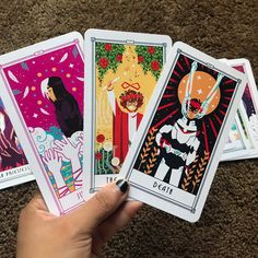 four different tarot cards being held up in the air by someone's hand