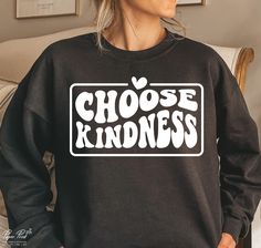 a woman wearing a black sweatshirt with the words choose kindness printed on it in white