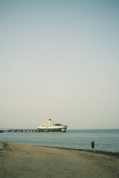 a person walking on the beach with a cruise ship in the background at low tide