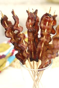 bacon sticks in a glass with toothpicks sticking out of the top, on a table