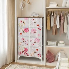 a white cabinet with pink flowers painted on the doors and drawers next to a window