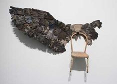 a wooden chair sitting next to a wall with wings on it