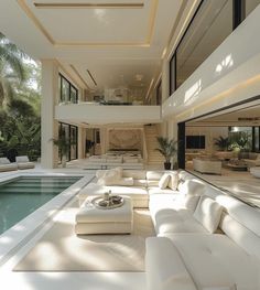 a large living room with white furniture next to a swimming pool