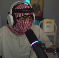 a man wearing headphones and a bandana sitting in front of a microphone