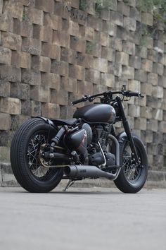 a black motorcycle parked in front of a wall with bricks on it's sides