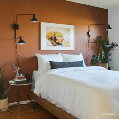 a bed sitting in a bedroom next to a wall mounted plant and a painting on the wall