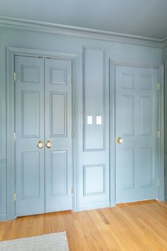 an empty room with blue walls and wooden floors is pictured in this image, there are three doors on each side of the room