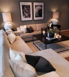 a living room filled with lots of furniture and candles on the coffee table in front of two framed pictures