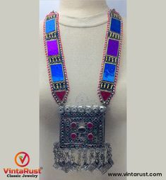 *This intriguing long-strap mala necklace with a square pendant is the epitome of tribal culture. This semi-hued square pendant with intricate design depicts the exceptional art of our Central Asian artists. The pendant and the black strap are beautified with multi-hued glass stones. Silver rhythmic bells are embellished at the bottom of this alluring pendant. *The length of this glorious tribal mala necklace is pretty good. The simple yet elegant tribal necklace is perfect for a casual occasion Traditional Rectangular Necklace For Festivals, Bohemian Square Multicolor Jewelry, Traditional Adjustable Rectangular Necklaces, Traditional Adjustable Rectangular Necklace, Traditional Multicolor Rectangular Necklace, Bohemian Multicolor Rectangular Jewelry, Traditional Handmade Rectangular Necklace, Handmade Traditional Rectangular Necklace, Bohemian Square Necklace As Gift