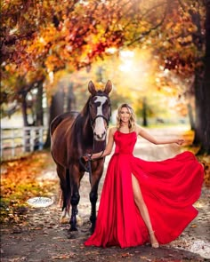 a woman in a red dress is standing next to a horse and posing for the camera