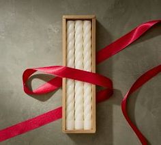 two white candles in a box tied with red ribbon