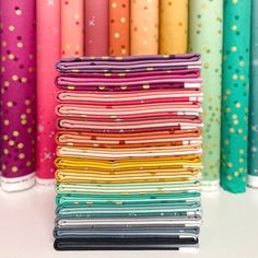 a stack of colorful papers sitting next to each other on a white table with lots of different colors