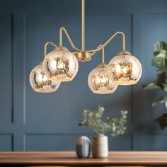 a chandelier with five glass balls hanging from it's arms and two vases on the table