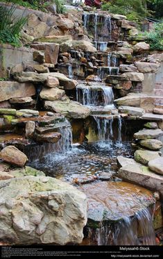 an outdoor waterfall with lots of rocks and water