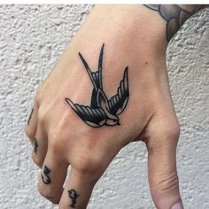 a hand with a bird tattoo on it's left thumb and the middle finger