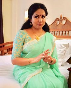 a woman sitting on top of a bed in a green sari