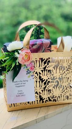 a paper bag with flowers on it sitting on top of a wooden table next to a sign