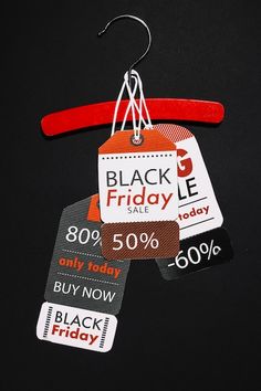 black friday sale tags hanging from a red hanger on a black background with text