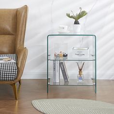 a glass shelf with books and other items on it in front of a brown chair